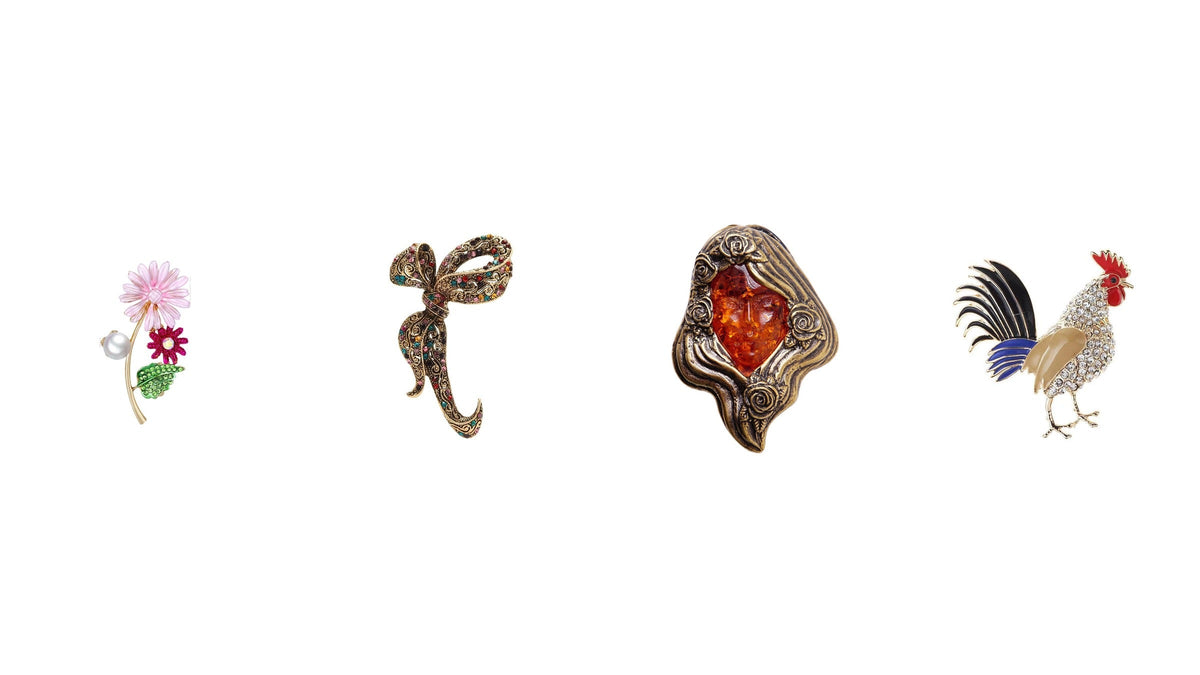Quatre broches au style ancien : fleur perlée, nœud orné de strass, ambre sculpté et coq émaillé Image